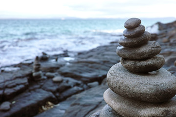 A pile of pebbles and rocks forming a balance act on a rocky beach.