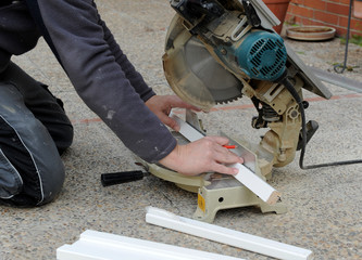 Carpenter by cutting a profile of white wood for a door frame