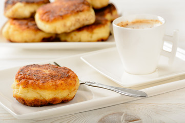 Cheese pancakes on white plate and cup of coffee.