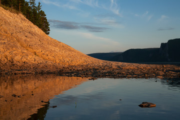 The rocky shore of the river, in the light of the setting sun. Lena river. Yakutia. Russia.