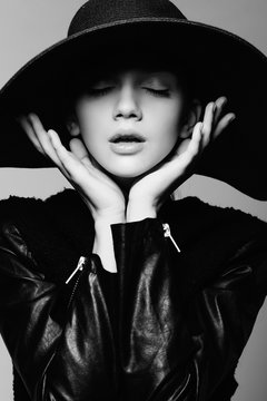 Portrait of a beautiful girl in a hat with eyes closed, posing in studio, black and white photography