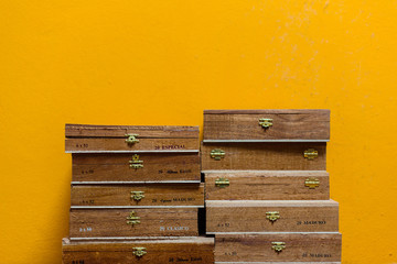 A stack of Cuban cigar boxes in front of a yellow wall.
