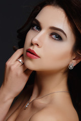 Beautiful woman with curly hair and evening make-up. Jewelry and Beauty