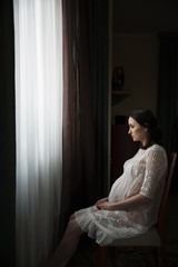 Pregnant woman sitting near a window