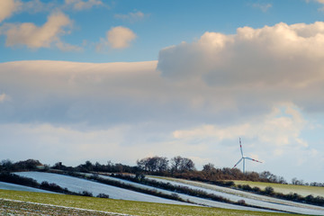 Fototapeta na wymiar Wind-turbine in landscape with clouds and with a little snow
