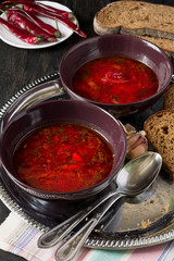 Two bowls with traditional Ukrainian vegetable borscht on the black wooden background