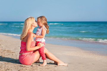 Young mother and her adorable daughter enjoying day at beach