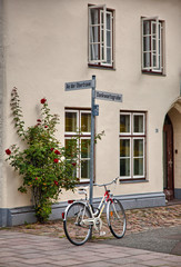 Fototapeta na wymiar Old building and a white bicycle resting on a lamp post in Lubeck, Germany