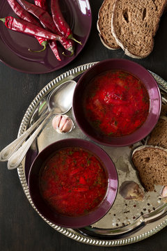 Two bowls with traditional Ukrainian vegetable borscht on the black wooden background