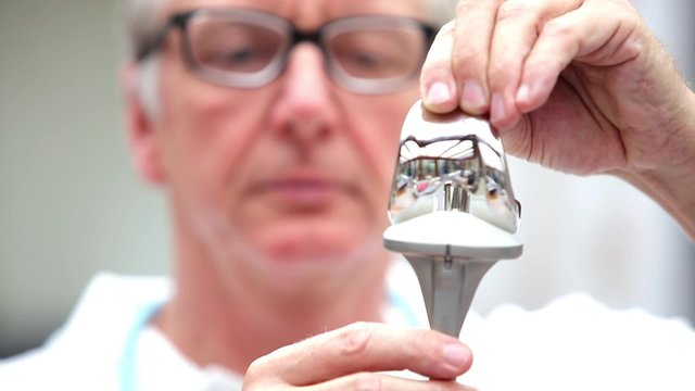 Mature doctor demonstrating total knee endoprosthesis