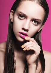 Portrait of a beautiful young girl in the studio on a pink background, beauty concept