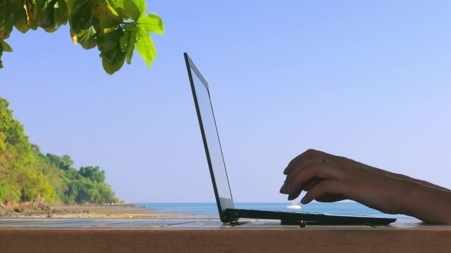 Girl working on a laptop on the beach. Business travel