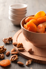 Dried apricots in a bowl on wooden board