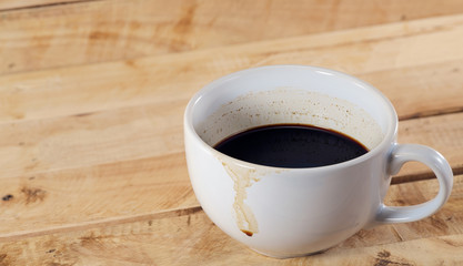 Coffee cup / Half a cup of coffee with stains on wood background.