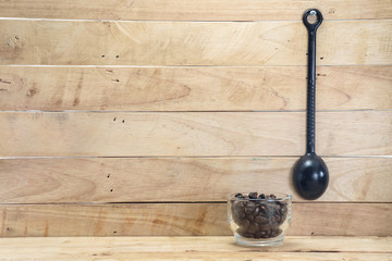 Coffee spoon and coffee beans / Coffee spoon hang on wooden wall and coffee beans in glass on...