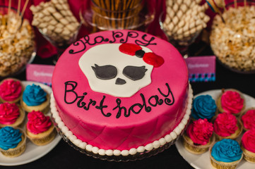 pink birthday cake with letters and cupcakes