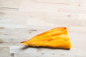 beautiful yellow smoked haddock fish fillet on a natural oak tree table