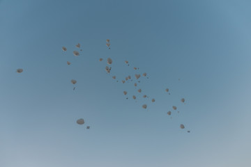 In den blauen Himmel aufsteigende weiße Luftballone mit Grußkarten am Band