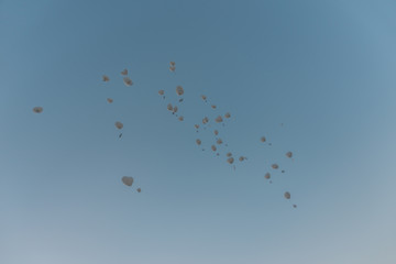 In den blauen Himmel aufsteigende weiße Luftballone mit Grußkarten am Band