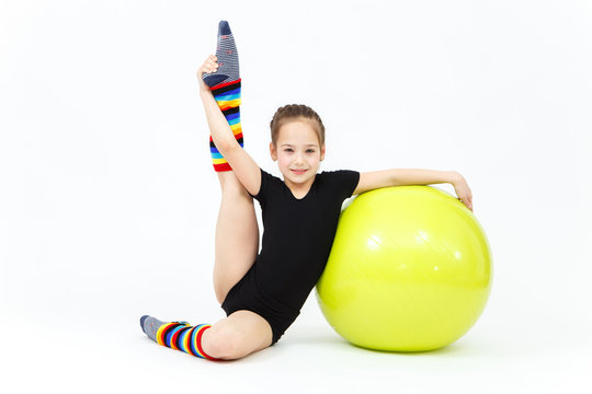 Flexible teen girl doing gymnastics exercises on fitness ball