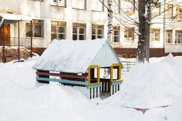 Домик на детской площадке, засыпанный снегом зимним днем