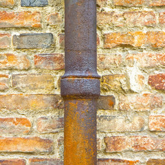 Detail of a downpipe against a brick wall - (Tuscany - Italy)