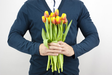 Man in a blue jacket holding a bouquet of tulips