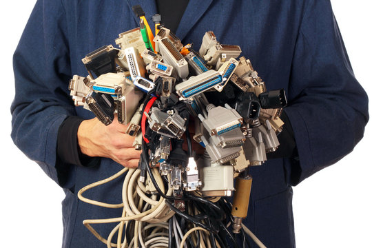Computer engineer holding many different cables wires connectors sockets and plugs, isolated on white