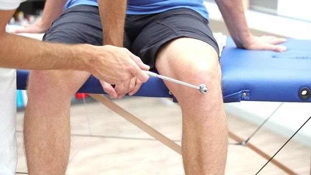 Medicine or physiotherapist performing patellatendonreflex test