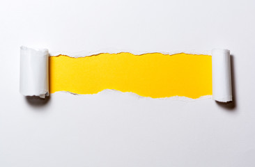 Ripped white paper with curled edges. Different colors under the white paper