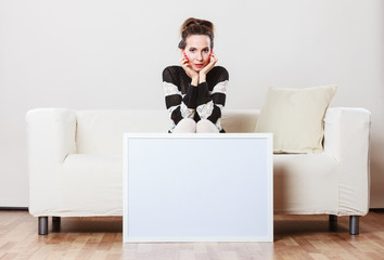 woman on sofa holding blank presentation board.