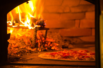 Thin crust pizza baking in wood fired oven