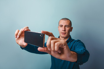 a man of European appearance thirty  years making self on the phone on a gray background