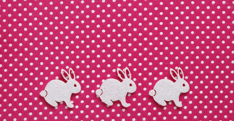 Three white easter bunnies on pink spotted background