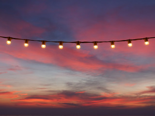 light bulbs on string wire against sunset sky