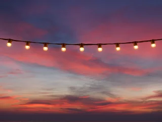 Crédence de cuisine en verre imprimé Mer / coucher de soleil light bulbs on string wire against sunset sky