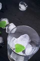 Fototapeta na wymiar glass with ice and mint on black background
