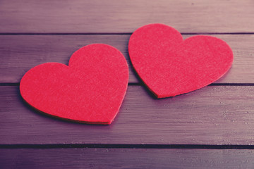Red felt hearts on purple wooden background