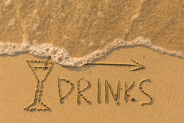 Word Drinks and arrow drawn on the sand of a beach with the soft wave.