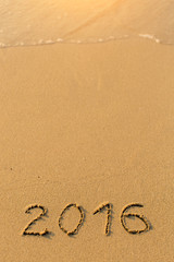 2016 - inscription on sand beach with the soft wave.