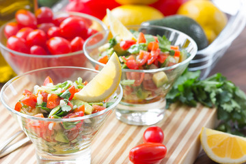 Sauce guacamole o salad in glass bowls and ingredients - avocado, tomatoes, lemon, cilantro and olive oil. Latinamerican food