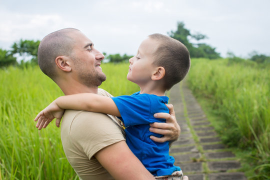 Young Happy Father Holding Up In His Arms Little Son