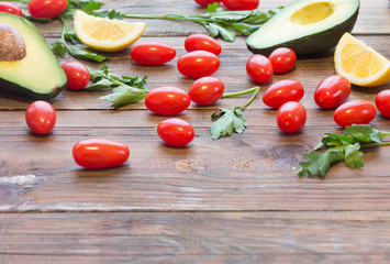 Ingredients for sauce guacamole. Fresh vegetables - avocado, tomatoes, cilantro and lemon. Vegetarian o healthy food concept