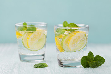 Mineral infused water with limes, lemons, ice and mint leaves on blue background, homemade detox soda water recipe