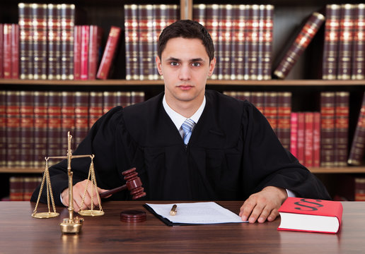 Portrait Of Young Judge Striking The Gavel At Table