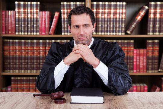 Serious Judge Thinking While Sitting At Desk