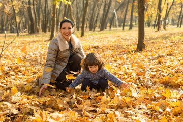 Happy mom and her toddler son in autumn park