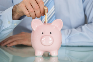 Businessman Inserting Note In Piggy Bank