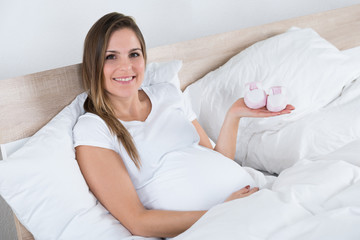 Obraz na płótnie Canvas Pregnant Woman Holding Baby Shoes