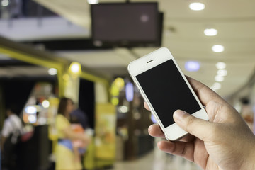 Hand on smartphone and blurred of people are walking in shopping center.